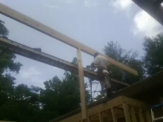 Carpenter setting a ridge beam over a new addition frame — Ice Dam Removal by Roofing Brothers in Muscatine
