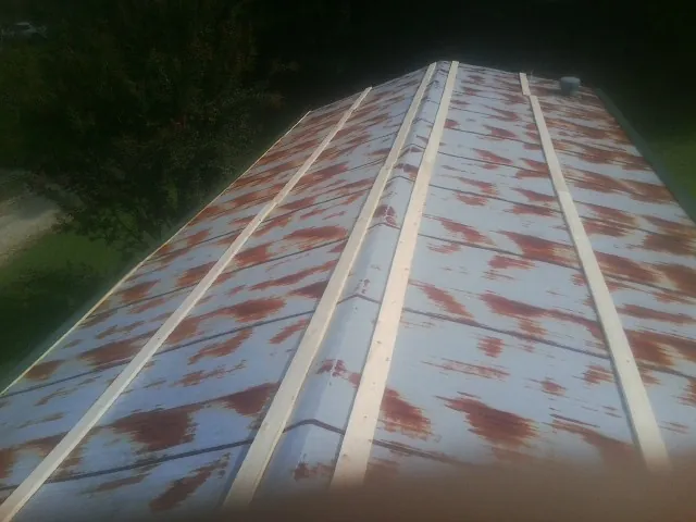 Rusted metal roof panels with new wood purlins before replacement — Storm Damage Roof Repair in Muscatine by Roofing Brothers
