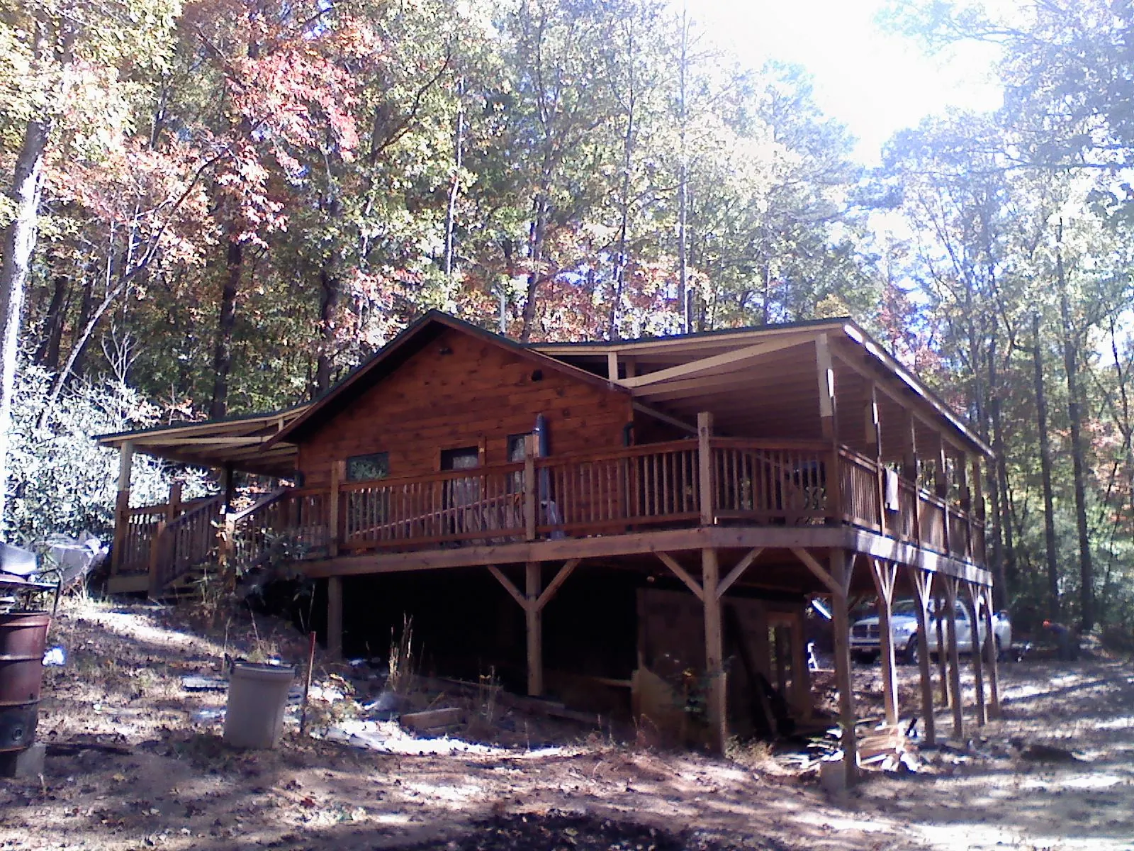 Log cabin with a wraparound porch and metal roof in the fall in Muscatine