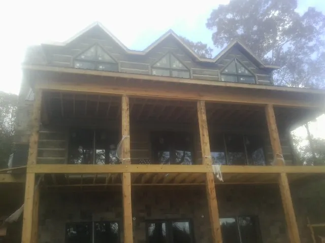 Dormers and porch framing on a large log home under construction — Roof Coating work by our crew in Muscatine