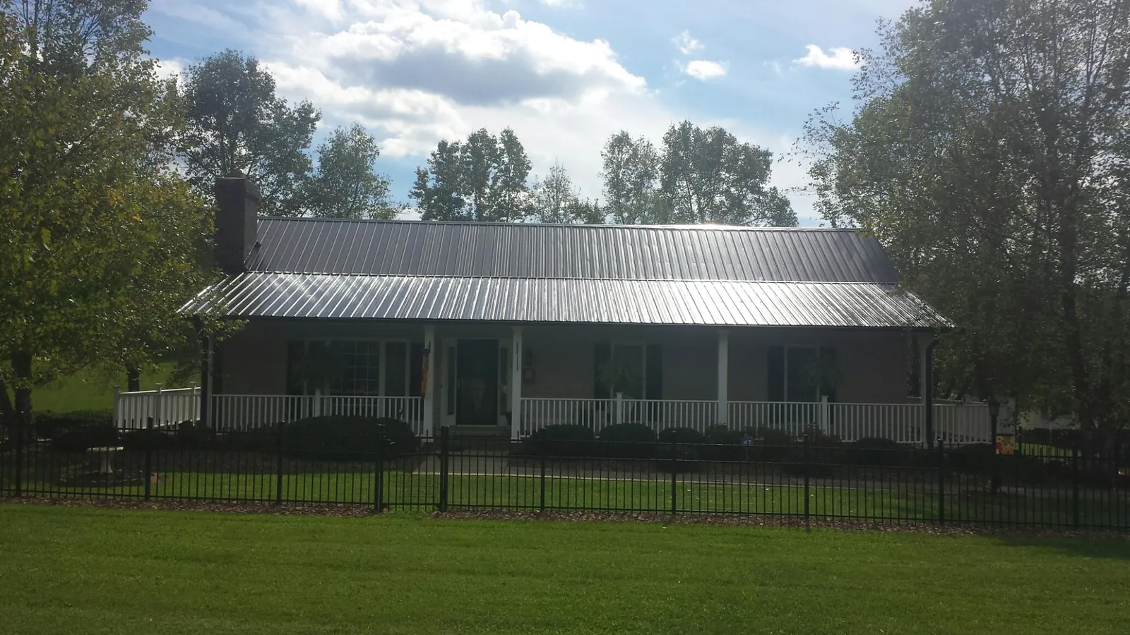Gray metal roof on a brick ranch with a full width front porch — Gutter Guard Installation work by our crew in Muscatine