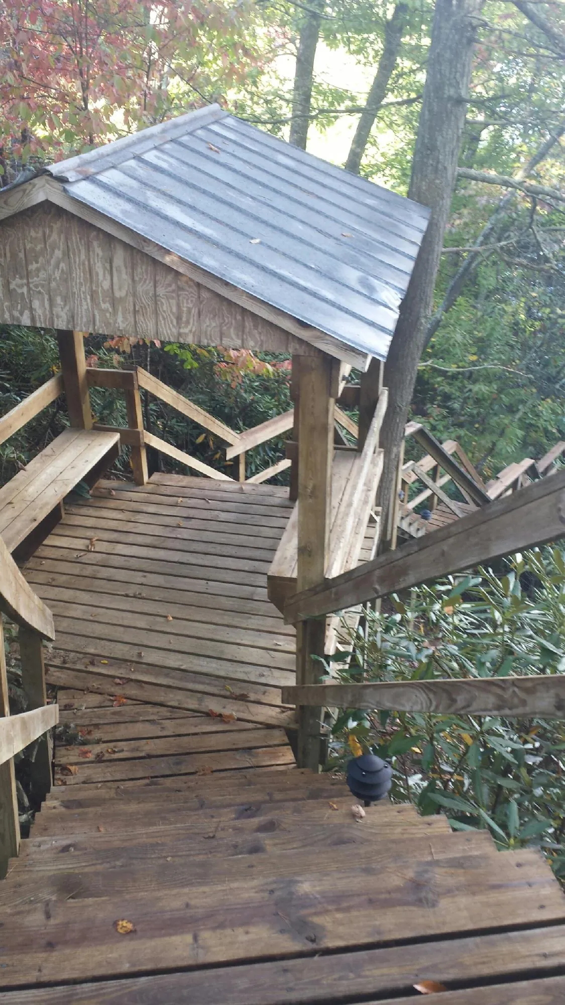 Metal roofed shelter over wooden steps on a wooded walkway — Skylight Repair & Installation work by our crew in Muscatine