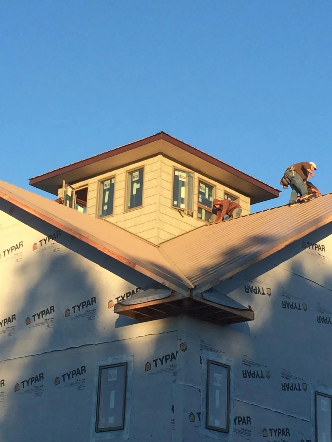 Roofers working around a rooftop cupola on a new metal roof at sunset — Roof Waterproofing in Muscatine by Roofing Brothers